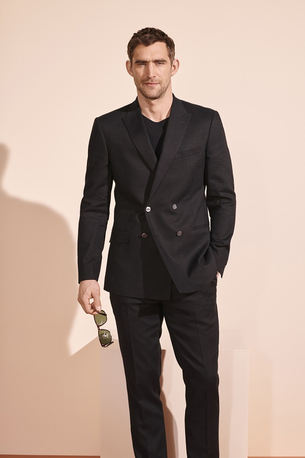 A man wearing a black suit from M&S.