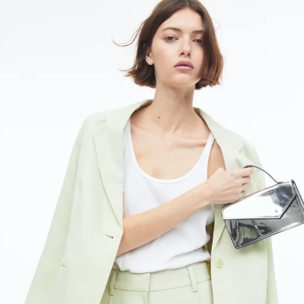 A model wearing a green pastel suit and a silver handbag