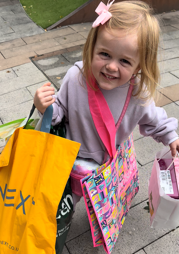 Callie is holding lots of shopping bags and smiling