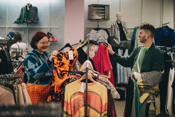 Two shoppers in the charity supermarket picking up clothes from rails